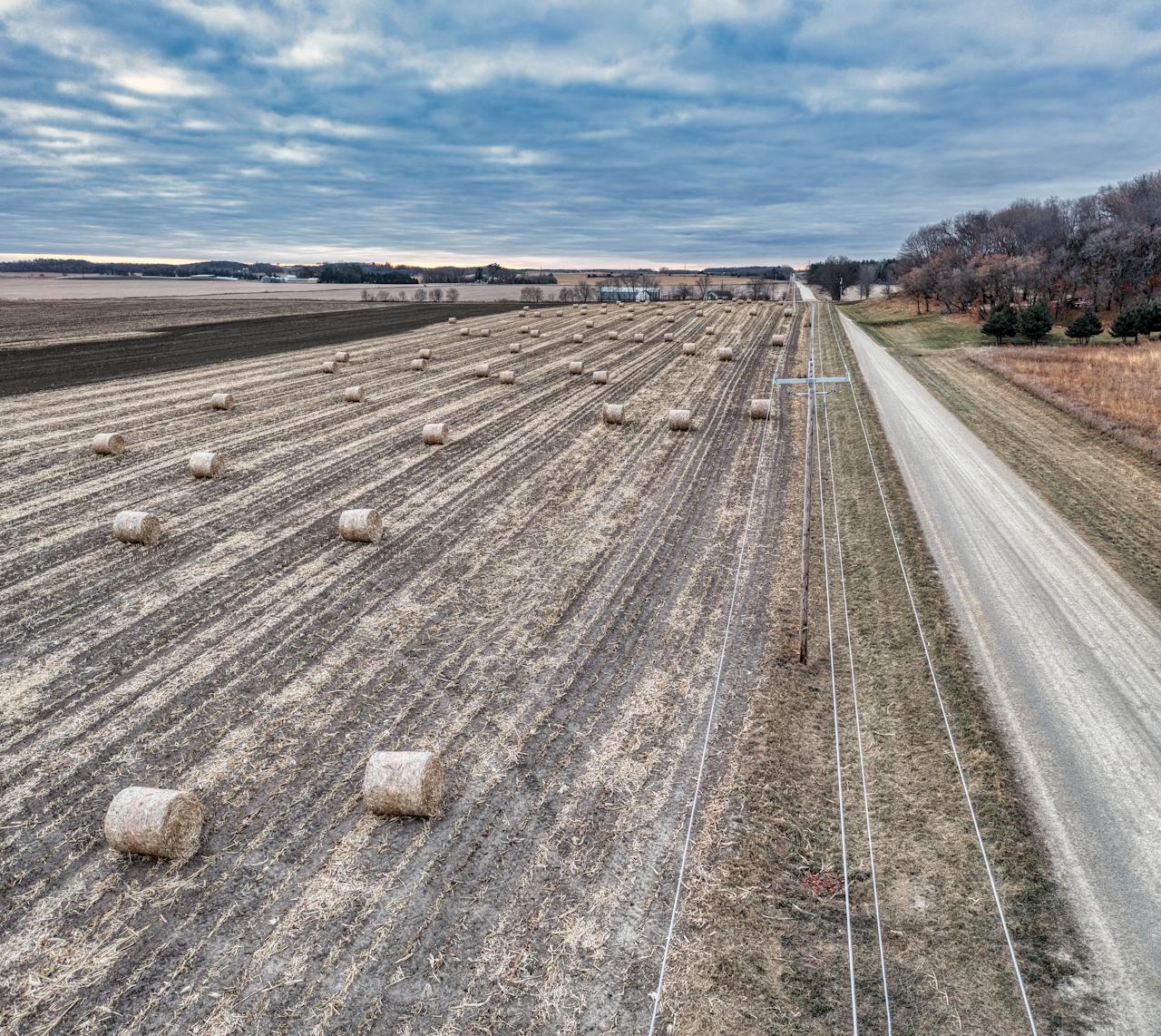 Aerial view showcasing hay bales and road in rural Elgin, MN, under overcast sky.